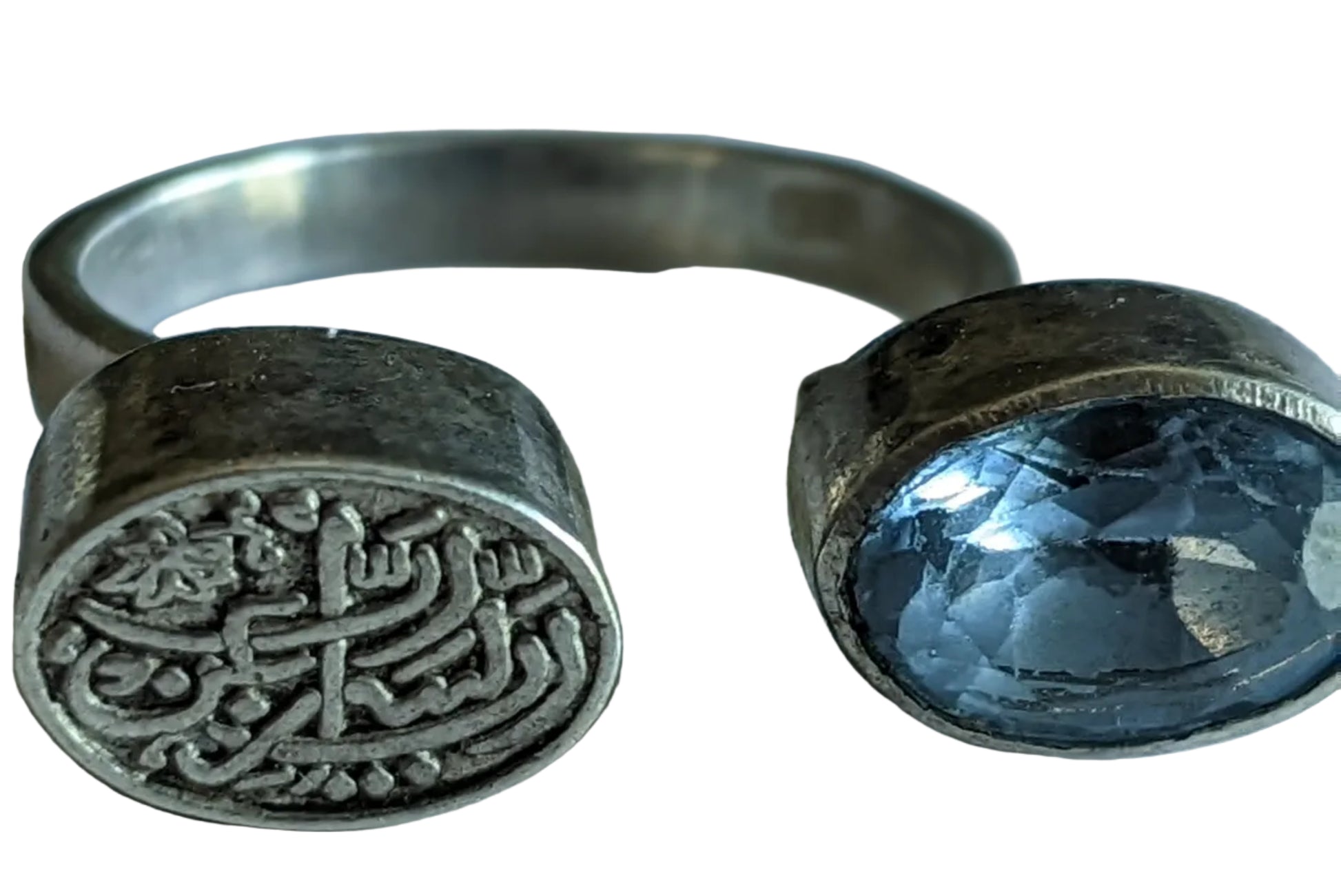 Silver ring with engraved design and blue gemstone on a white background