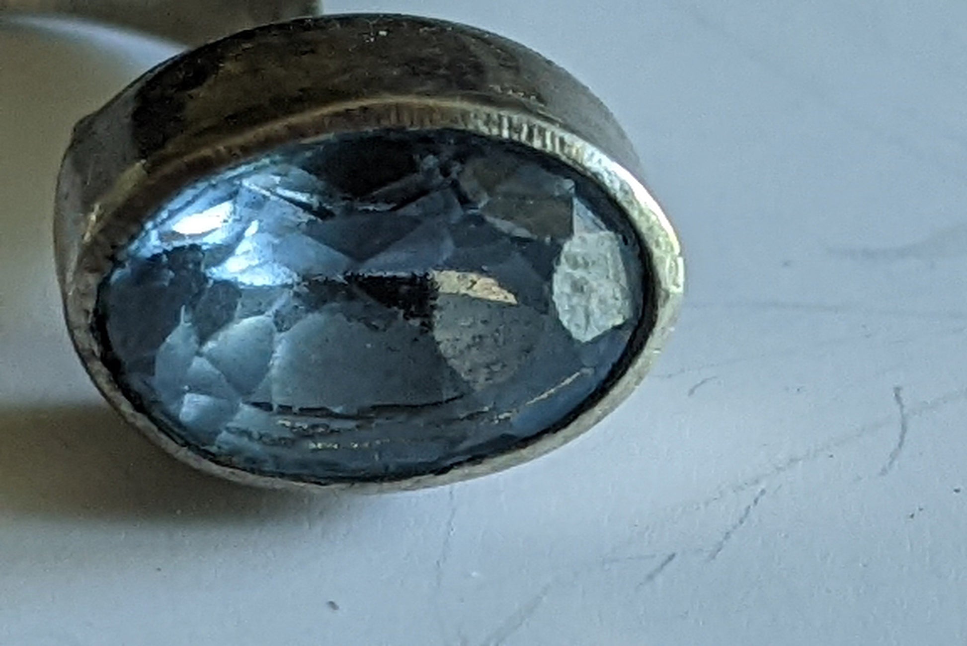 detail of a faceted blue topaz cabochon in a silver ring on a white background