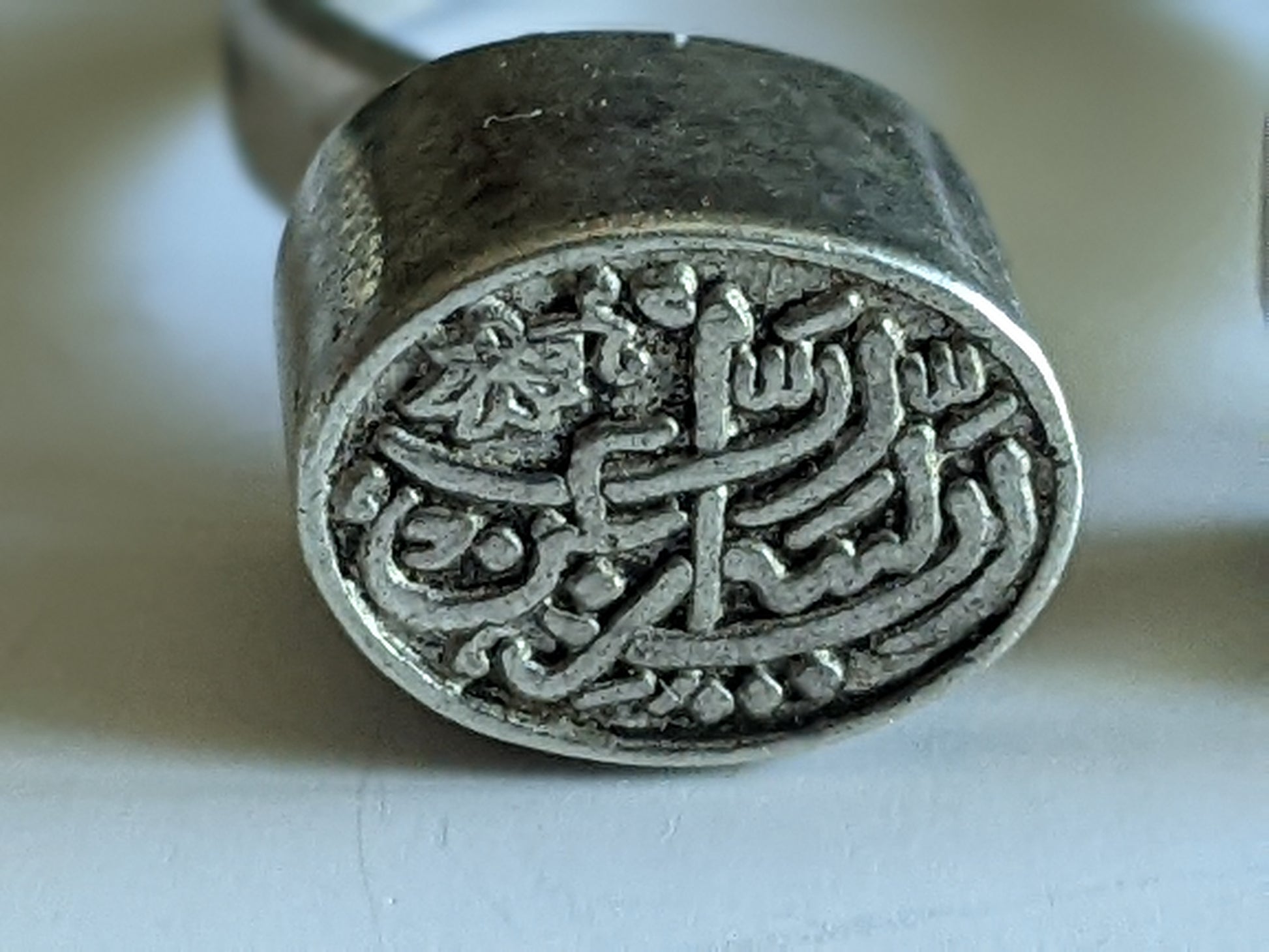 Silver ring with intricate design on a light background