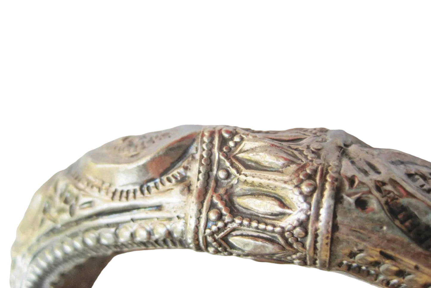 Close-up of a dent in a silver bangle bracelet against a plain light background.