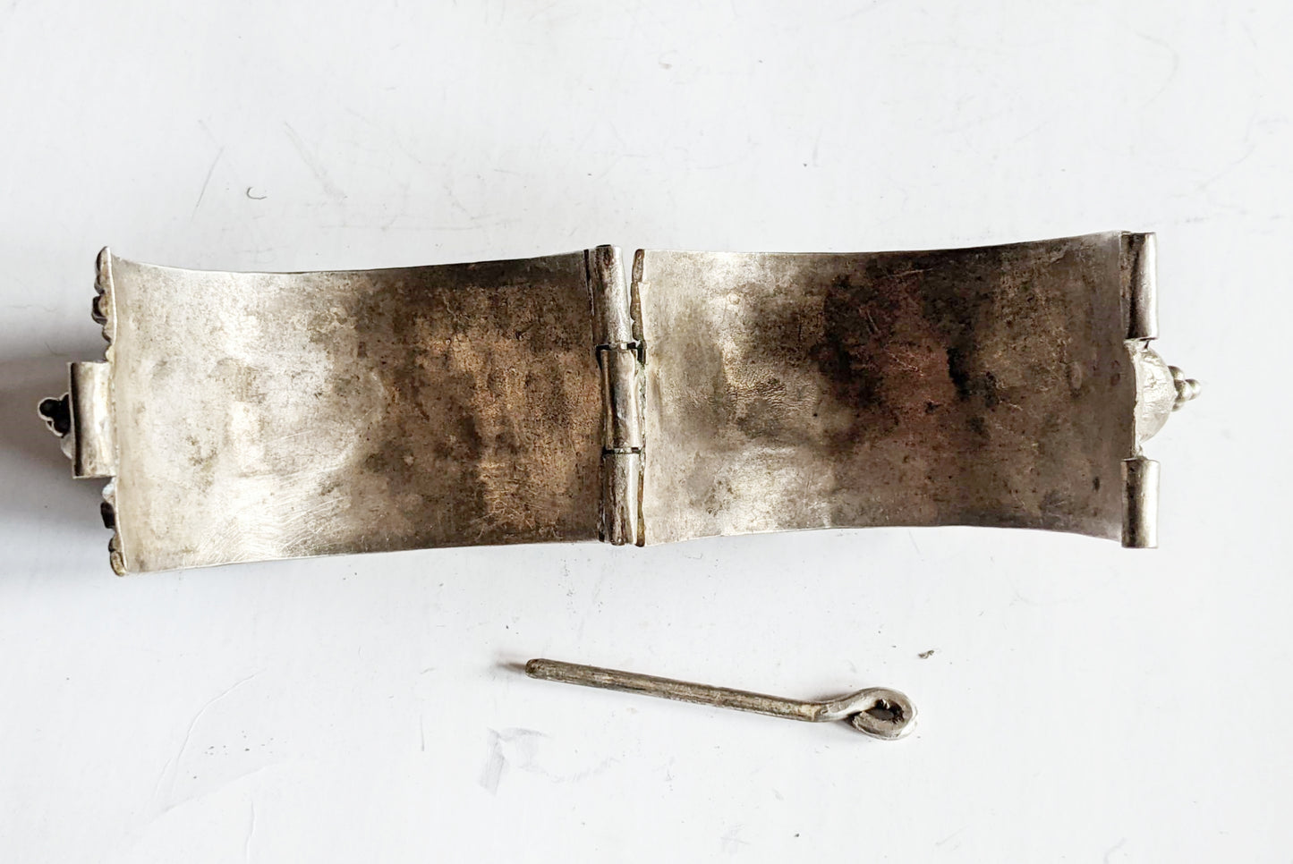 Silver bracelet with a pin closure on a white background