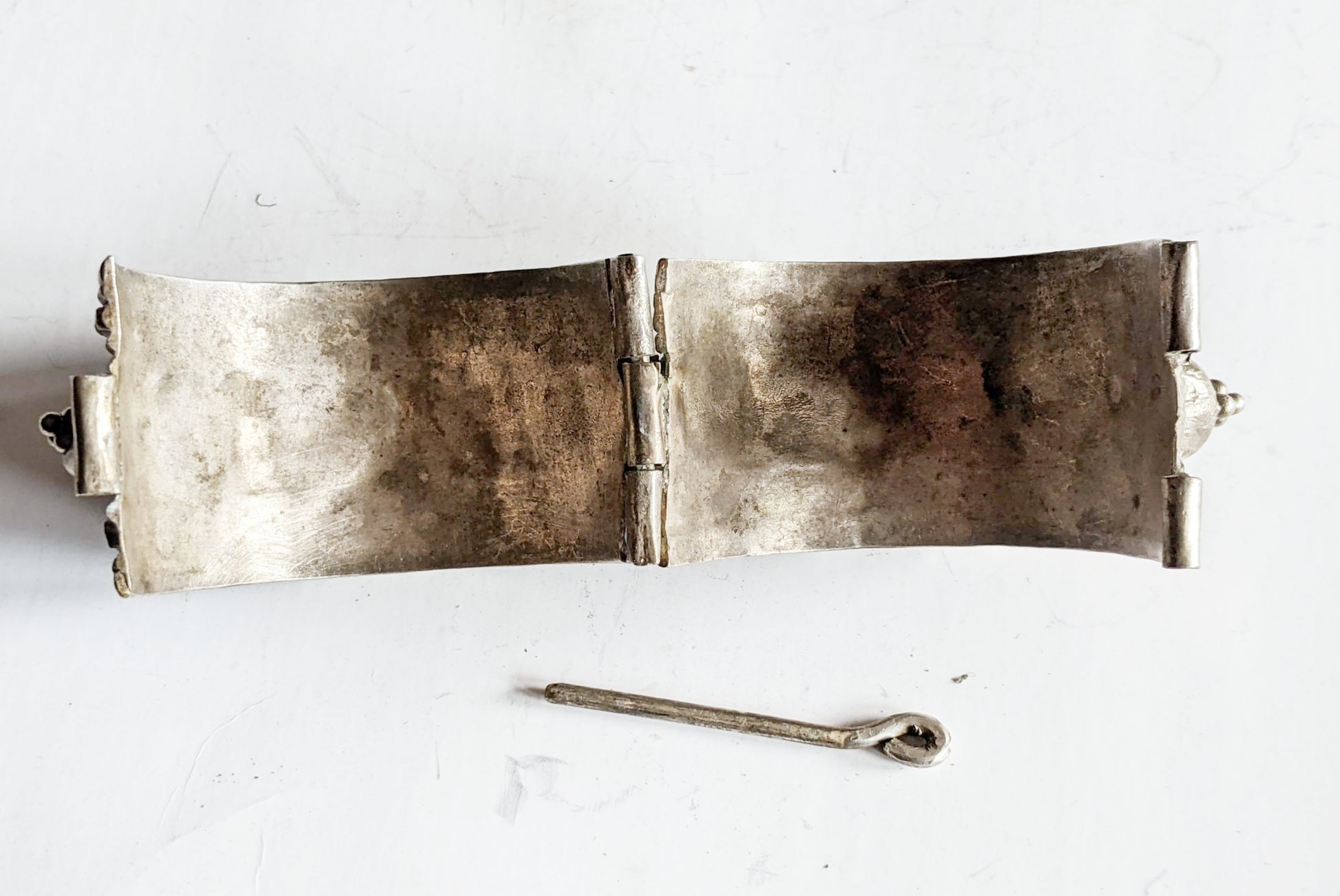 Silver bracelet with a pin closure on a white background