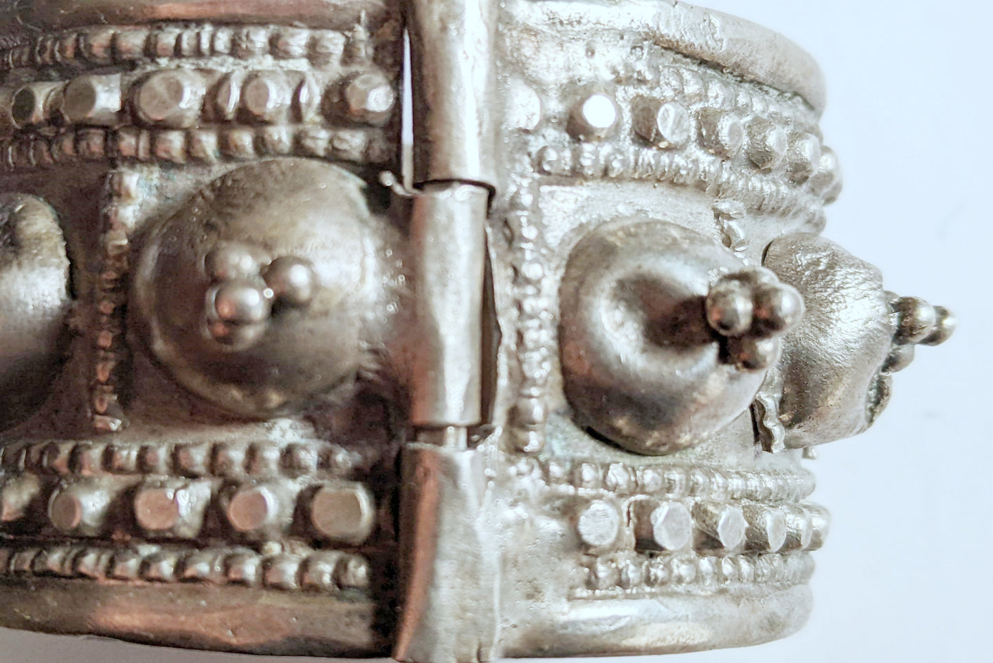 Close-up of a silver bracelet with intricate designs on a light gray background
