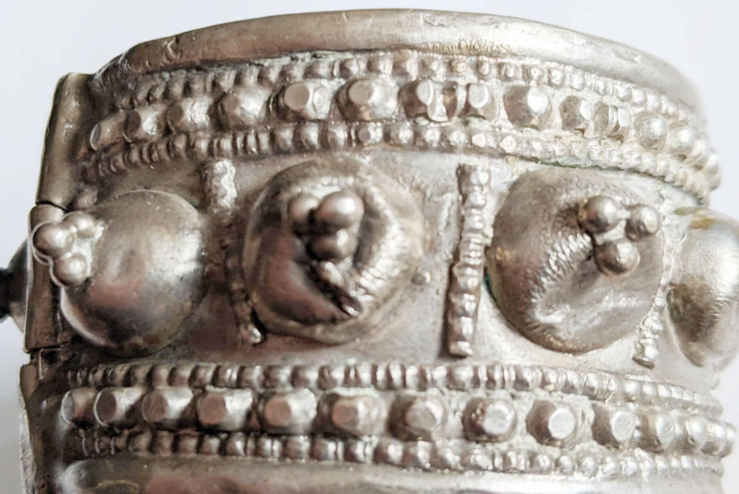 Close-up of a silver bracelet with intricate designs on a white background